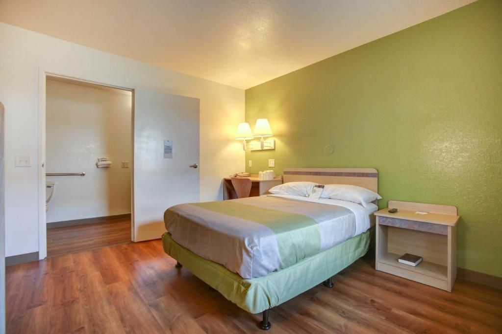 A hotel room with a bed, bedside tables, a nightstand, and a door.