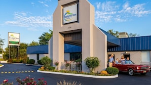 A Budget Inn with a modern design, a parking lot, and a red car parked outside.