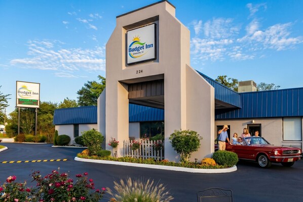 A Budget Inn with a modern design, a parking lot, and a red car parked outside.