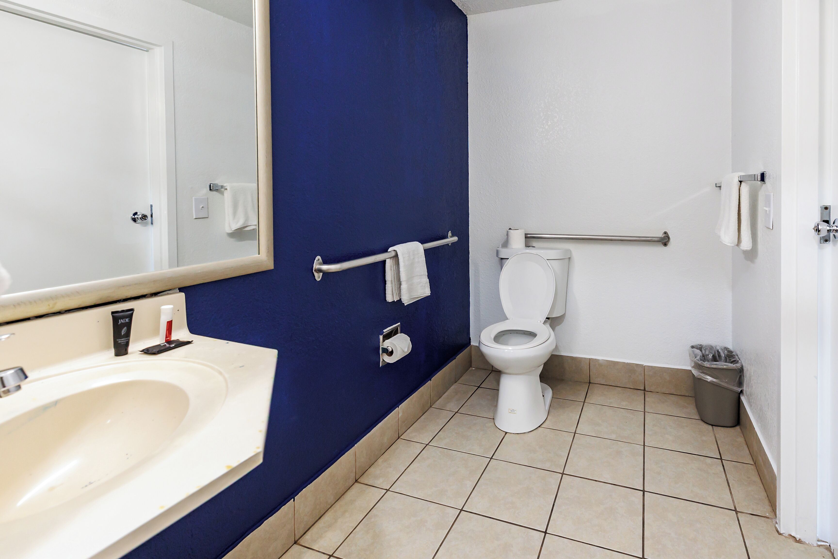 A bathroom with a white sink, a toilet, and a blue wall.