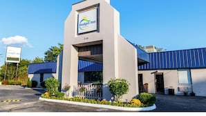 A Budget Inn with a modern design, featuring a prominent sign, a parking lot, and a well-maintained exterior with a blue roof and white walls.