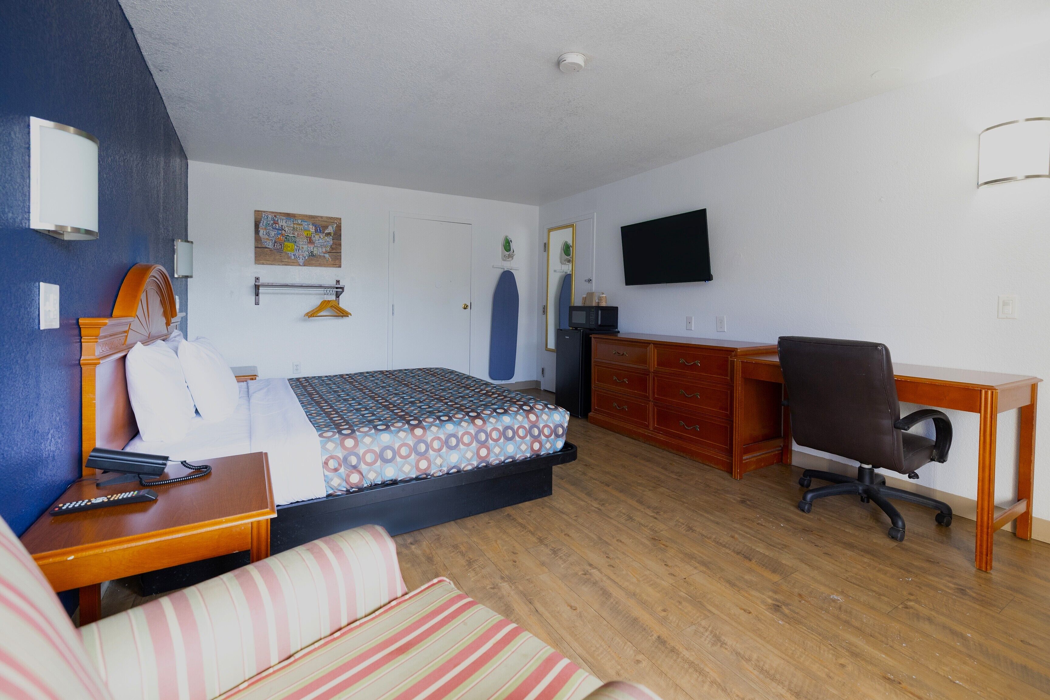Una camera d'albergo con un letto, una scrivania, una sedia, una TV e una mappa appesa al muro.