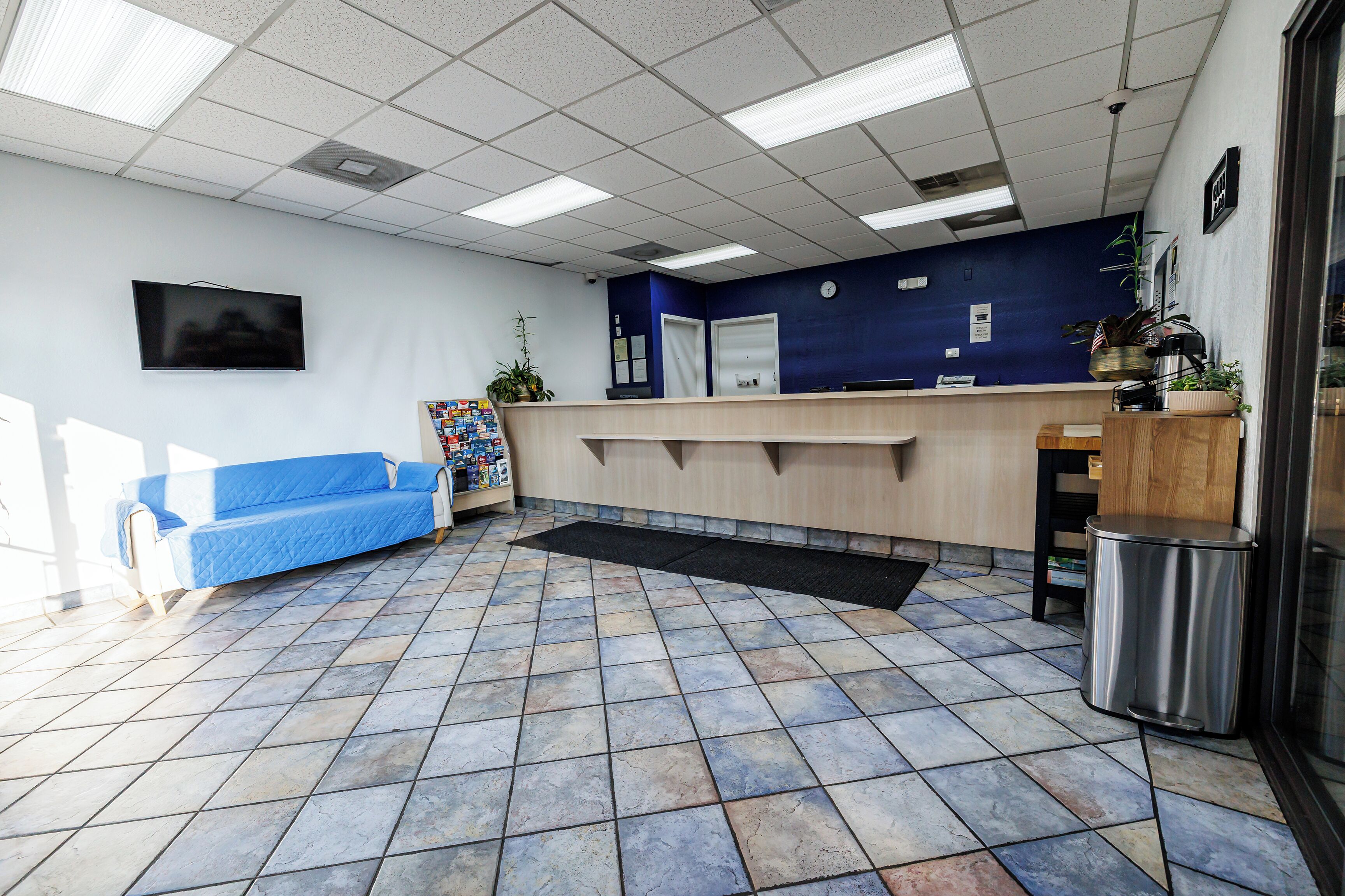 A reception area with a blue sofa, a reception desk, and a tiled floor.