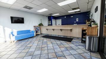 A reception area with a blue sofa, a reception desk, and a tiled floor.