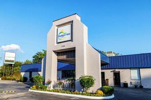 A Budget Inn with a modern design, featuring a prominent sign, a parking lot, and a well-maintained exterior with a blue roof and white walls. - Budget Inn Greenville By Hotel O I-85  (Greenville)