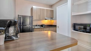 Een moderne keuken met een roestvrijstalen koelkast, een koffiezetapparaat en een magnetron.