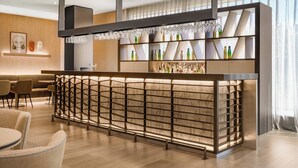 Un área de bar moderna con un separador de madera, estantes de vidrio y una variedad de botellas.