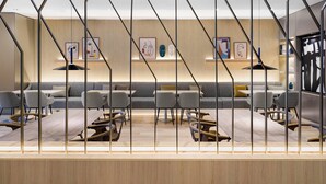 Un interior moderno con suelo de madera, sofás grises y una zona de comedor central con mesas y sillas.