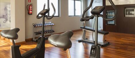 A gym with stationary bikes, treadmills, and dumbbells.