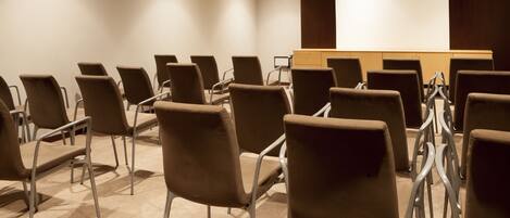 A conference room with rows of chairs, a podium, and a projection screen.