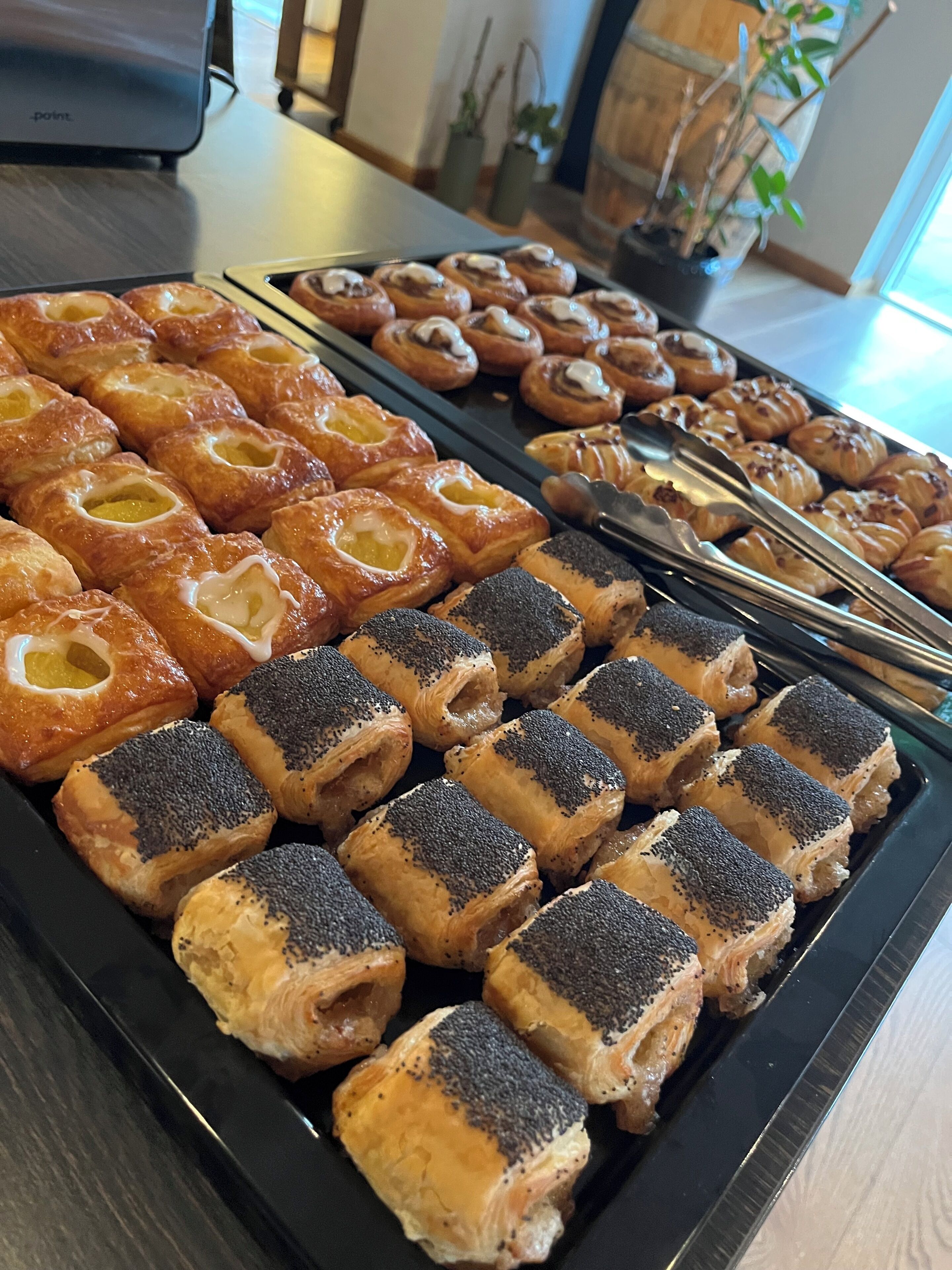 A tray of assorted pastries including puff pastries and croissants, arranged on a black tray.