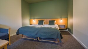 A neatly arranged bedroom with a bed, bedside tables, and a chair. - Hotel Hedemarken (Grindsted)