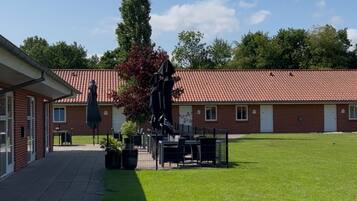 A building with a red-tiled roof, a paved walkway, and a grassy area.