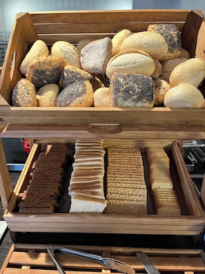 A wooden display case containing various types of bread and crackers.