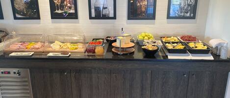 Una mesa de buffet con diversos alimentos y una selección de cuadros en la pared.