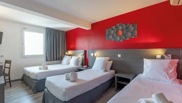 Habitación de hotel con dos camas, un escritorio y una ventana con cortinas.