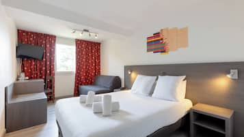 A modern hotel room with a large bed, a desk, a chair, and a TV.