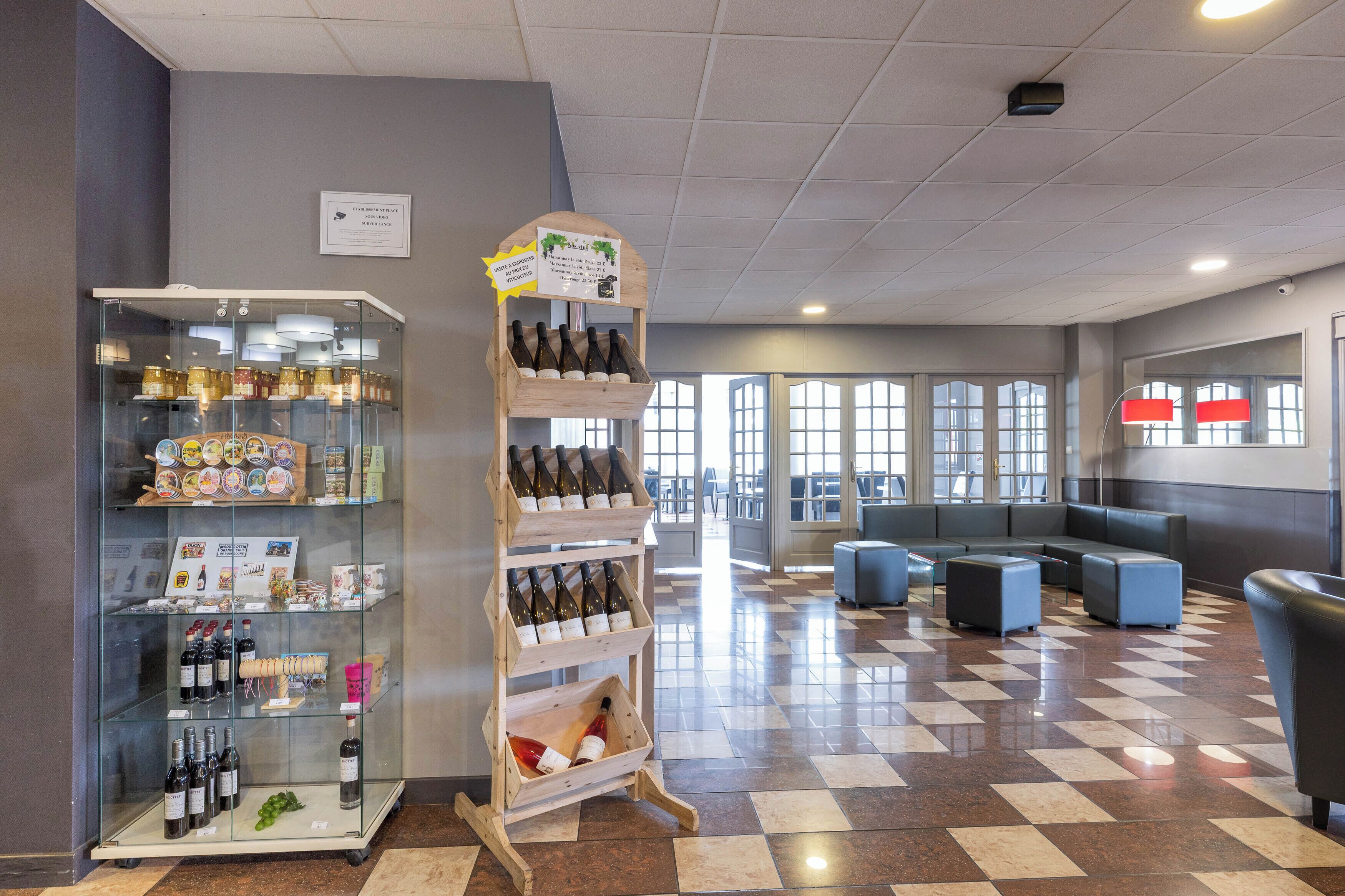 Een hotel lobby met een wijnrek, een zithoek en grote ramen.