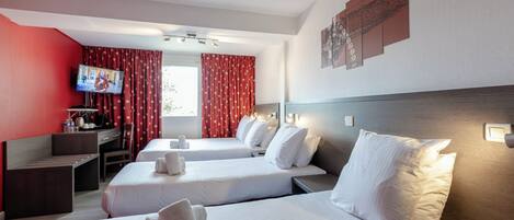 Habitación de hotel con dos camas, un escritorio, un televisor y cortinas rojas.