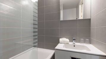 A modern bathroom with a bathtub, a sink, and a mirror.
