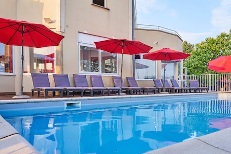 Una piscina al aire libre de temporada, sombrillas