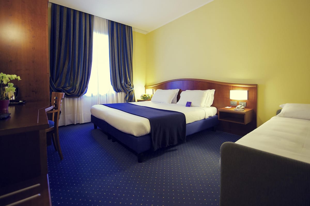 A hotel room with a large bed, a desk, and a chair.