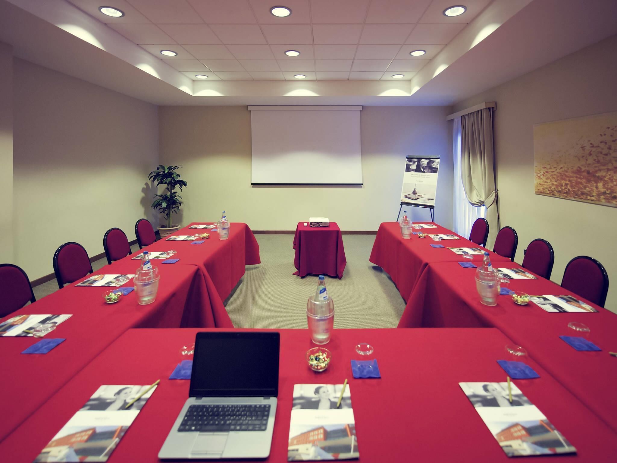 A conference room with red tablecloths, laptops, water bottles, and brochures.