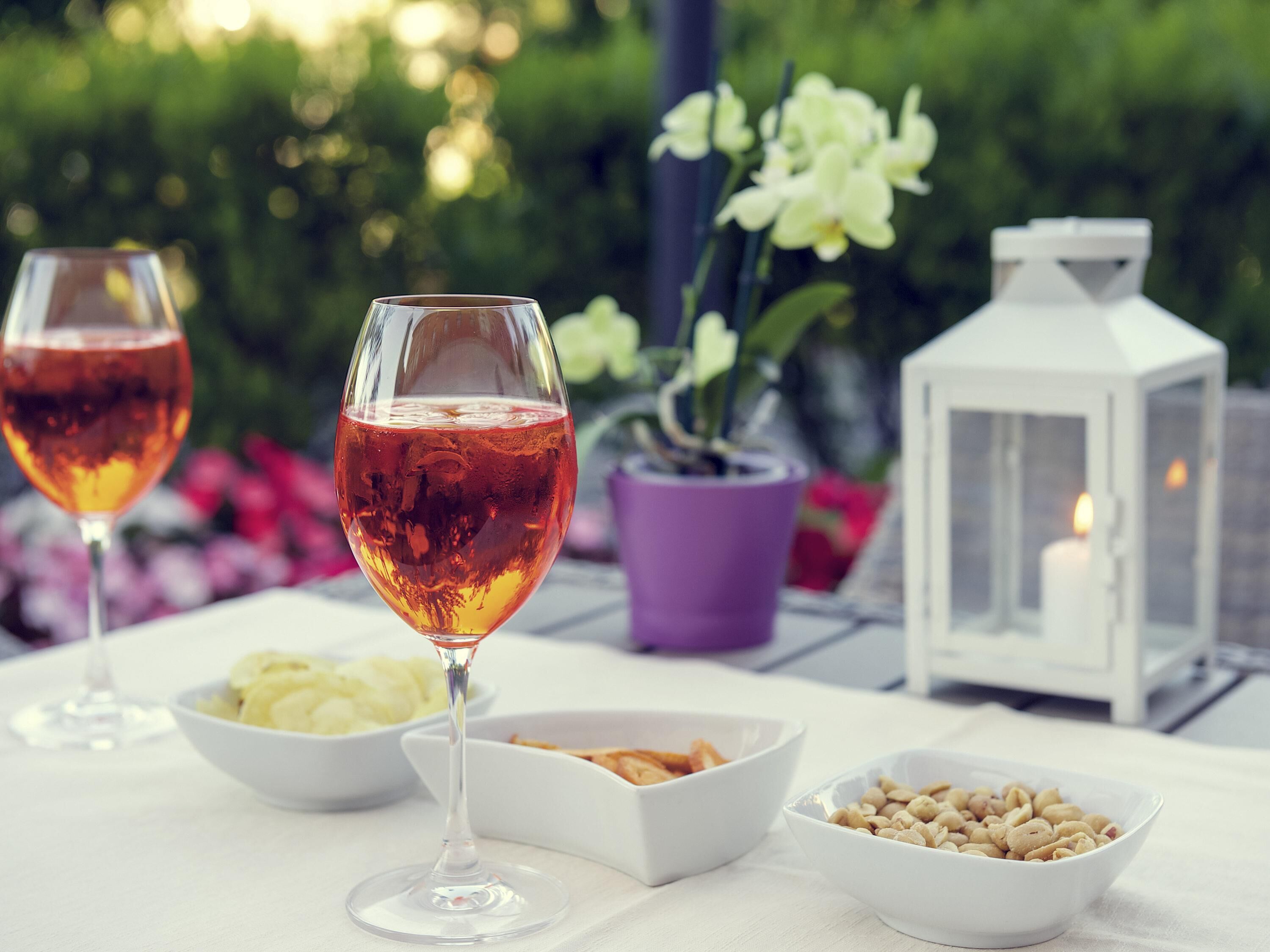 Two wine glasses on a table with bowls of food and a white lantern.