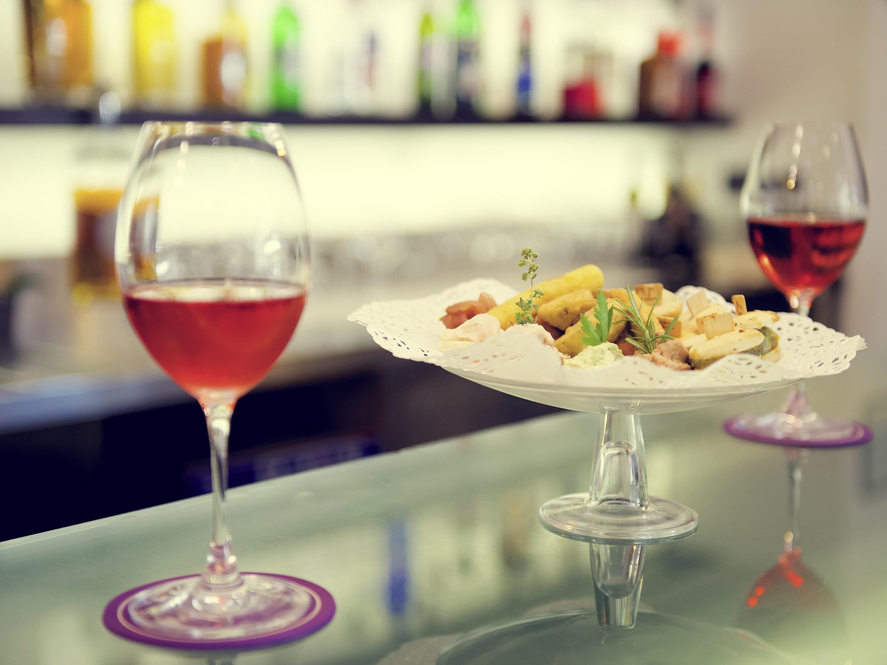 A bar setting with two wine glasses and a plate of food.