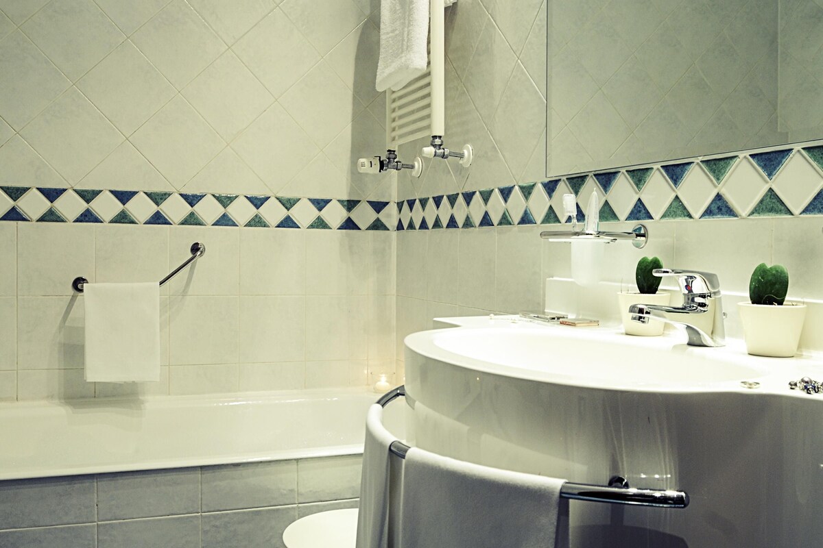 A bathroom with a bathtub, a sink with a mirror, and a towel rack.