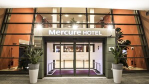 The entrance to Mercure Hotel with a modern design, featuring large glass doors and potted plants. - Mercure Genova San Biagio (Genoa)