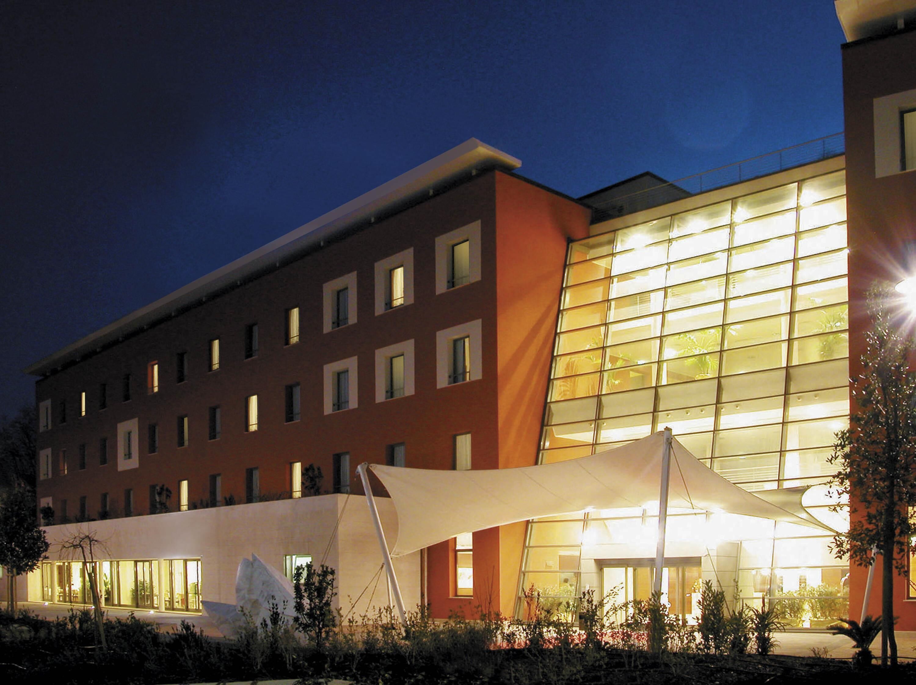 A hotel with a modern facade, large windows, and a covered outdoor area.