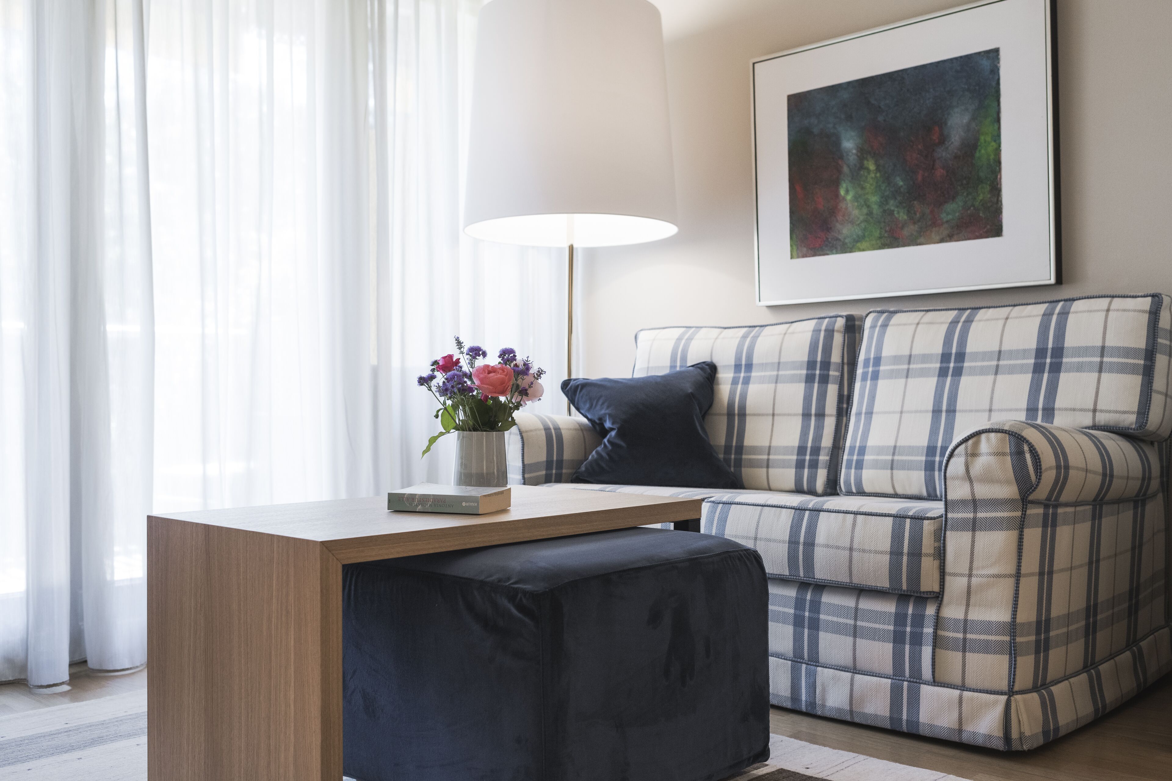 Una sala moderna con una mesa de centro de madera, un sofá escocés y un cojín azul oscuro.