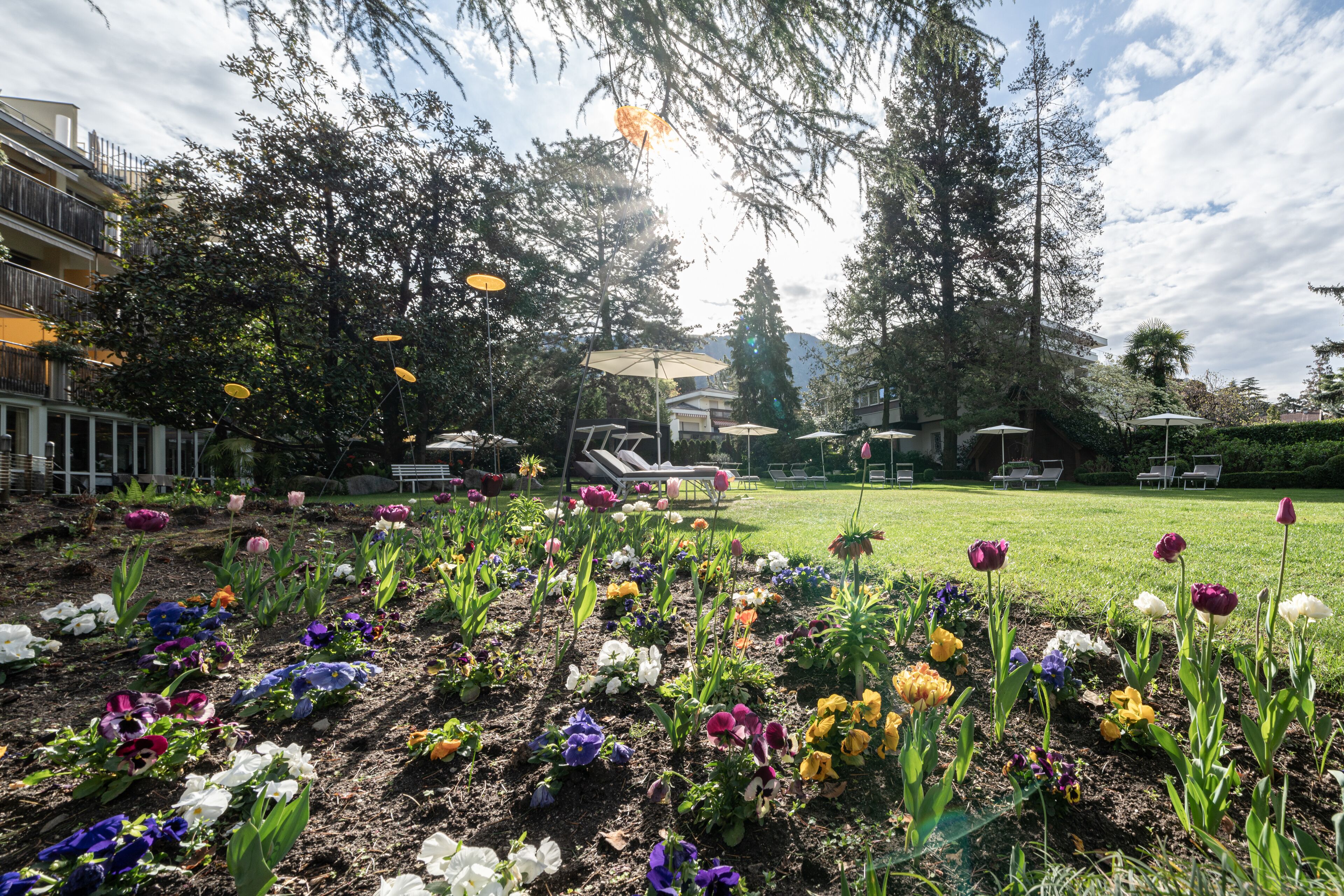 Um jardim com diversos tipos de flores e áreas de estar ao ar livre.