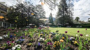 Um jardim com diversos tipos de flores e áreas de estar ao ar livre.