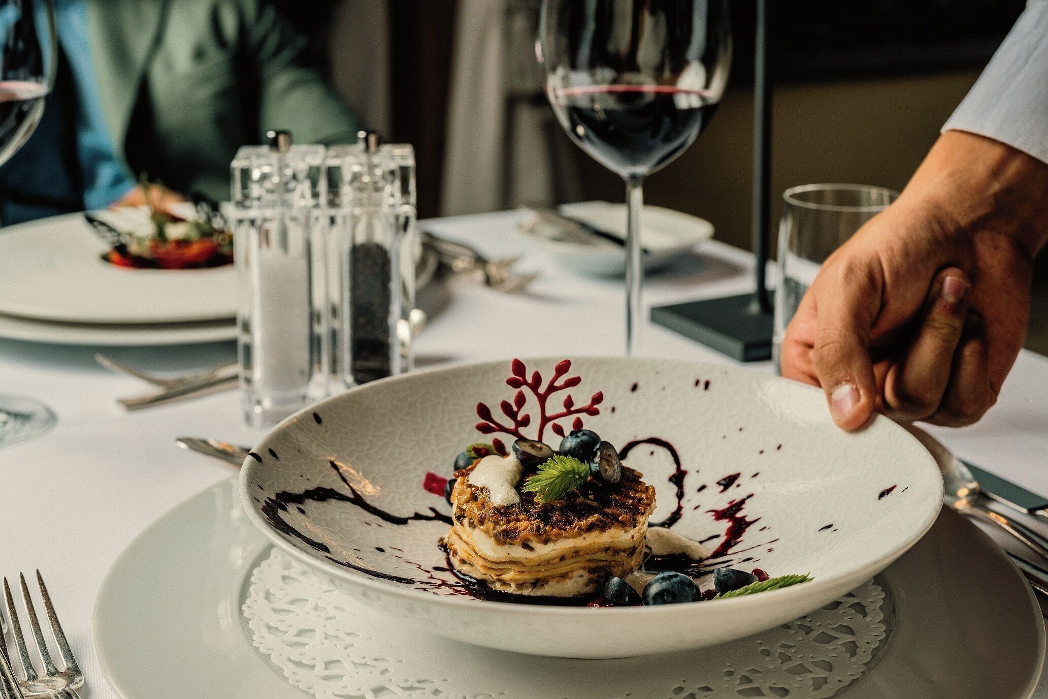 A dessert plate with a layered pastry, blueberries, and a decorative sauce on a white plate.