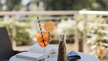 A round table with a drink, a book, and a small vase on a balcony.