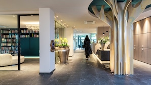A modern hotel lobby with a central walkway, a seating area, and a large bookshelf.