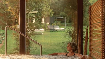 Ein Whirlpool mit Blick auf einen Garten und eine Terrasse.