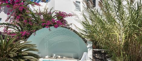 A pool area with a white building, a stone wall, and a chair.