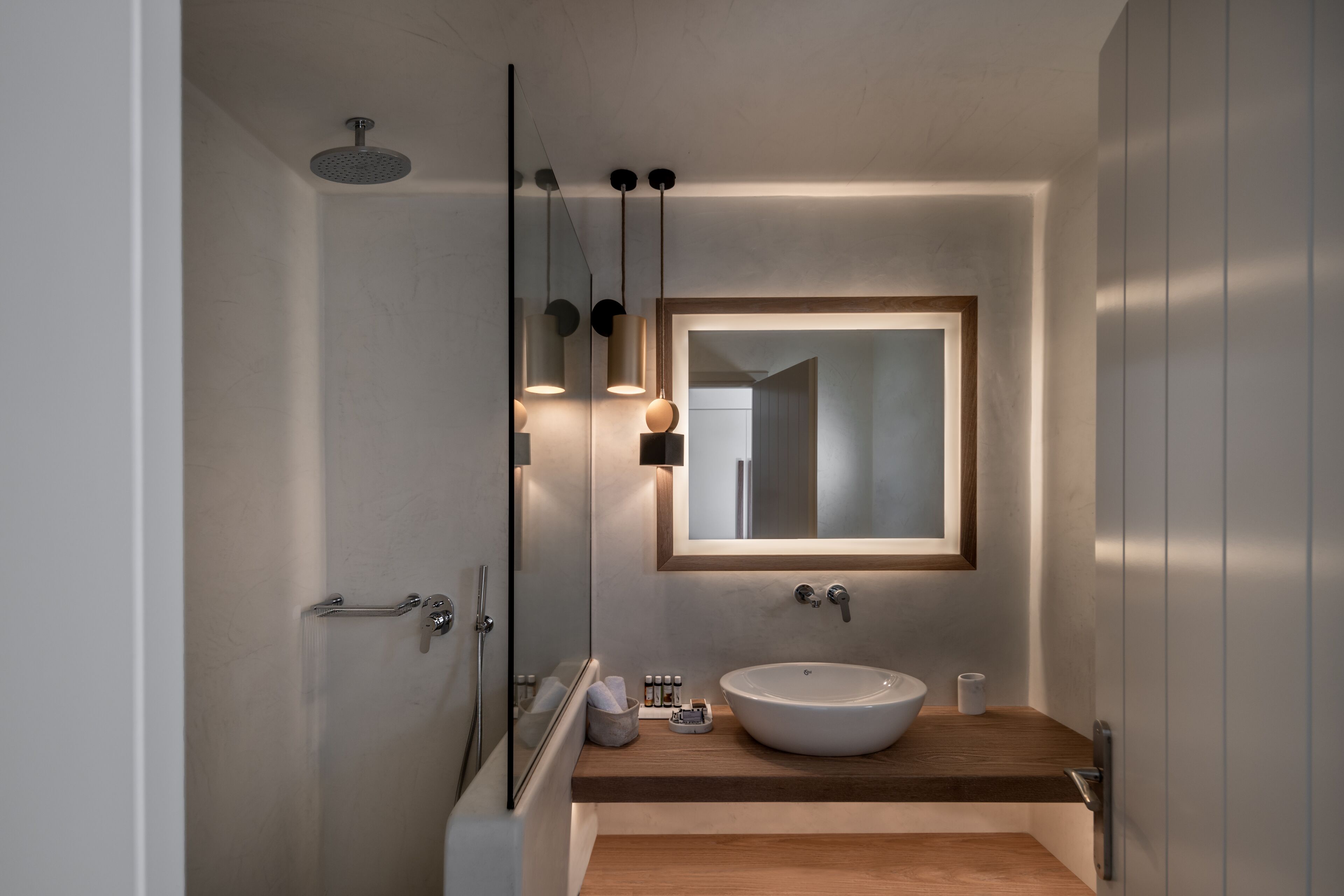 A modern bathroom with a large mirror, a round sink, and a shower.