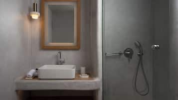 Un baño moderno con un lavabo blanco, un espejo con marco de madera y una ducha con cabezal de ducha manual.