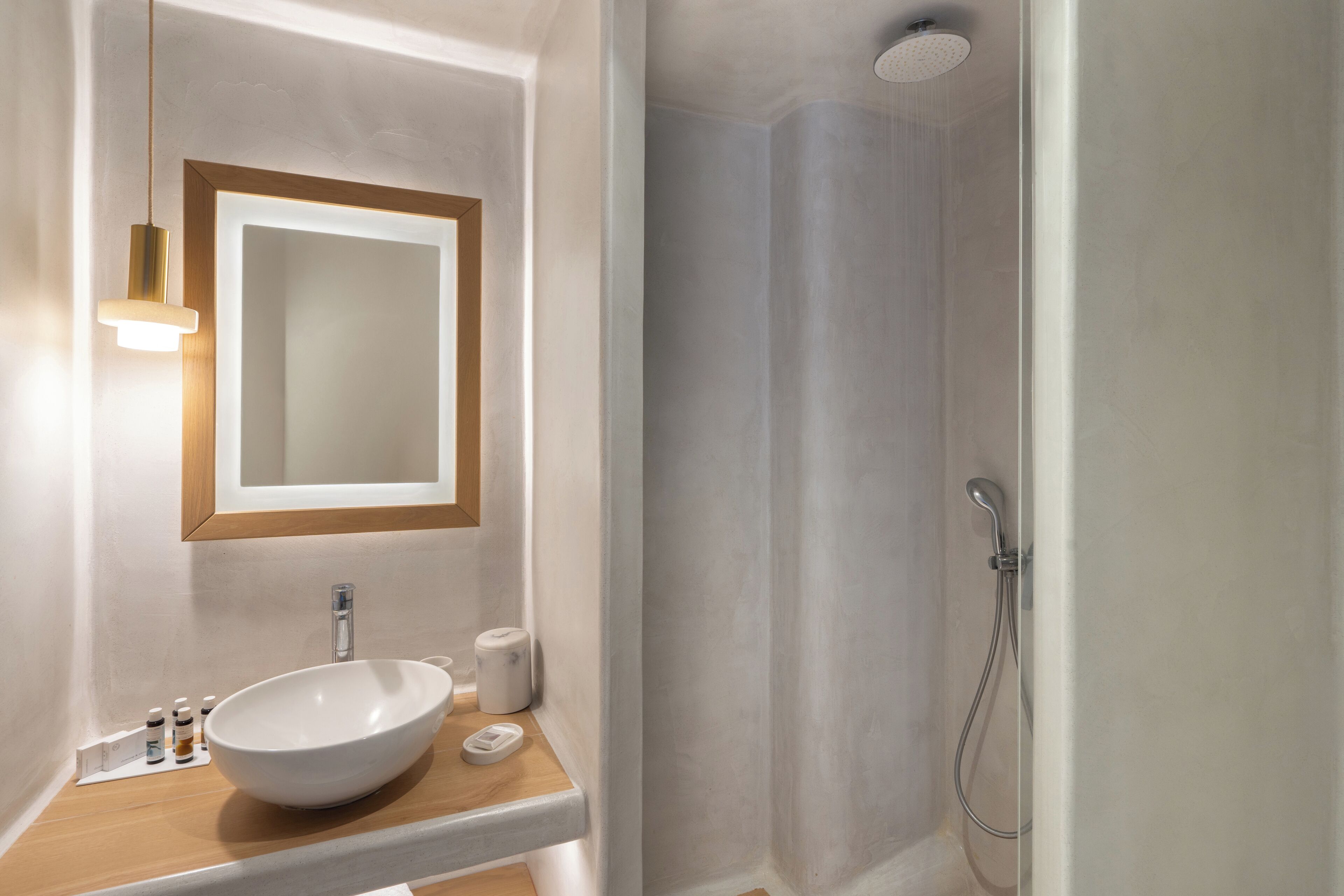 A modern bathroom with a large white sink, a mirror, and a shower.