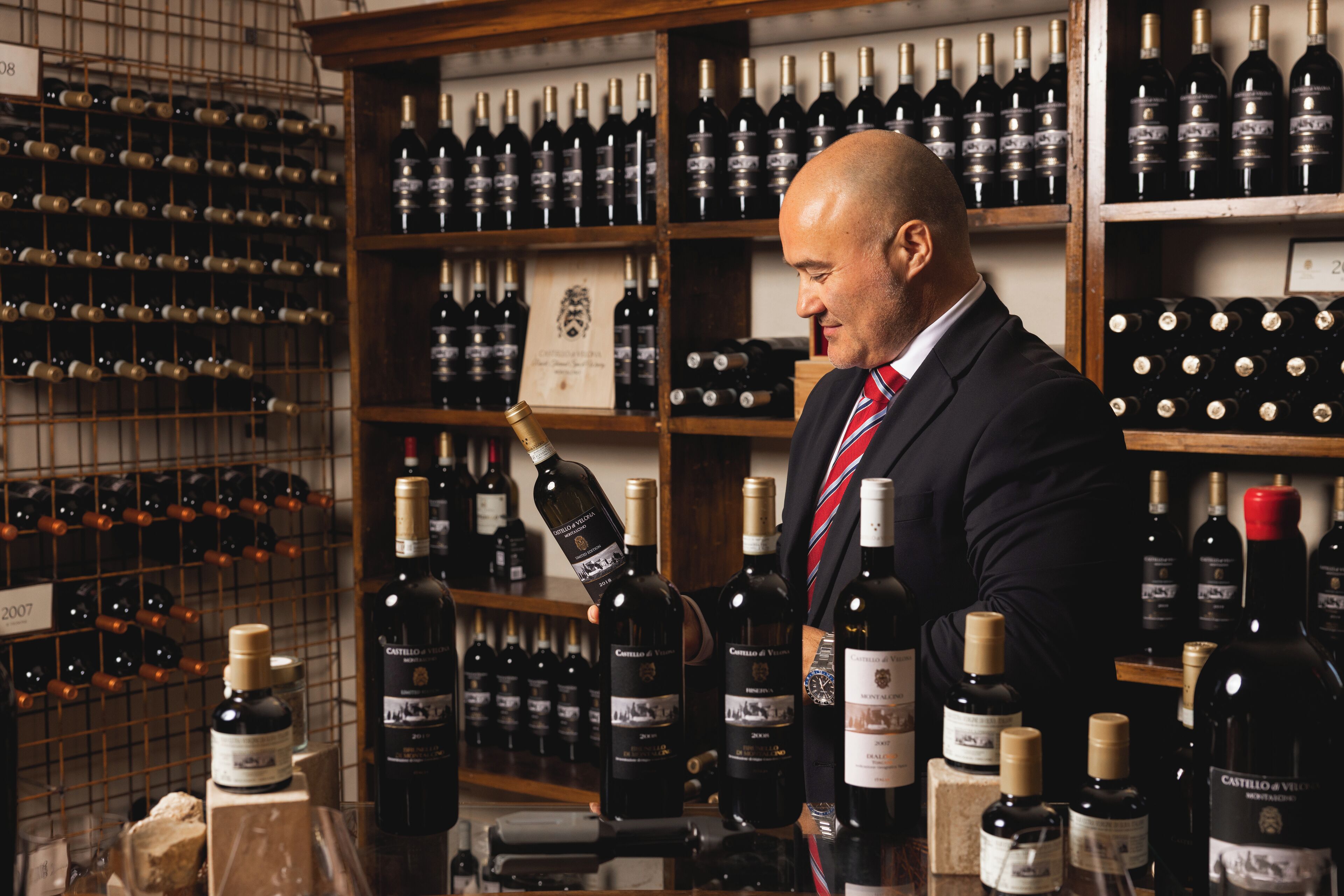 Un hombre con traje observa botellas de vino en una bodega bien surtida.