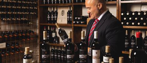 Un hombre con traje observa botellas de vino en una bodega bien surtida.