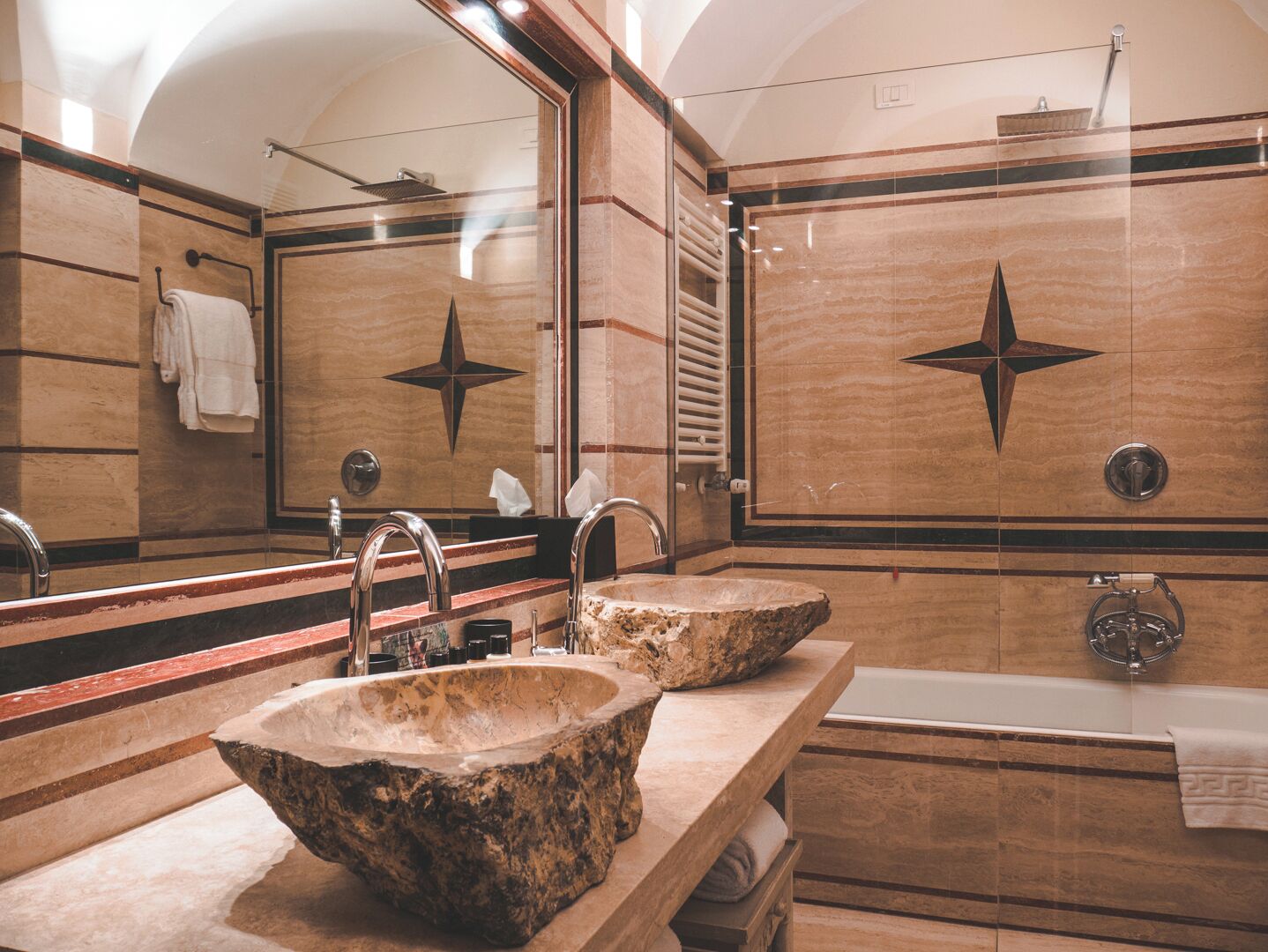Un baño con dos lavamanos de piedra, un espejo grande y una bañera.