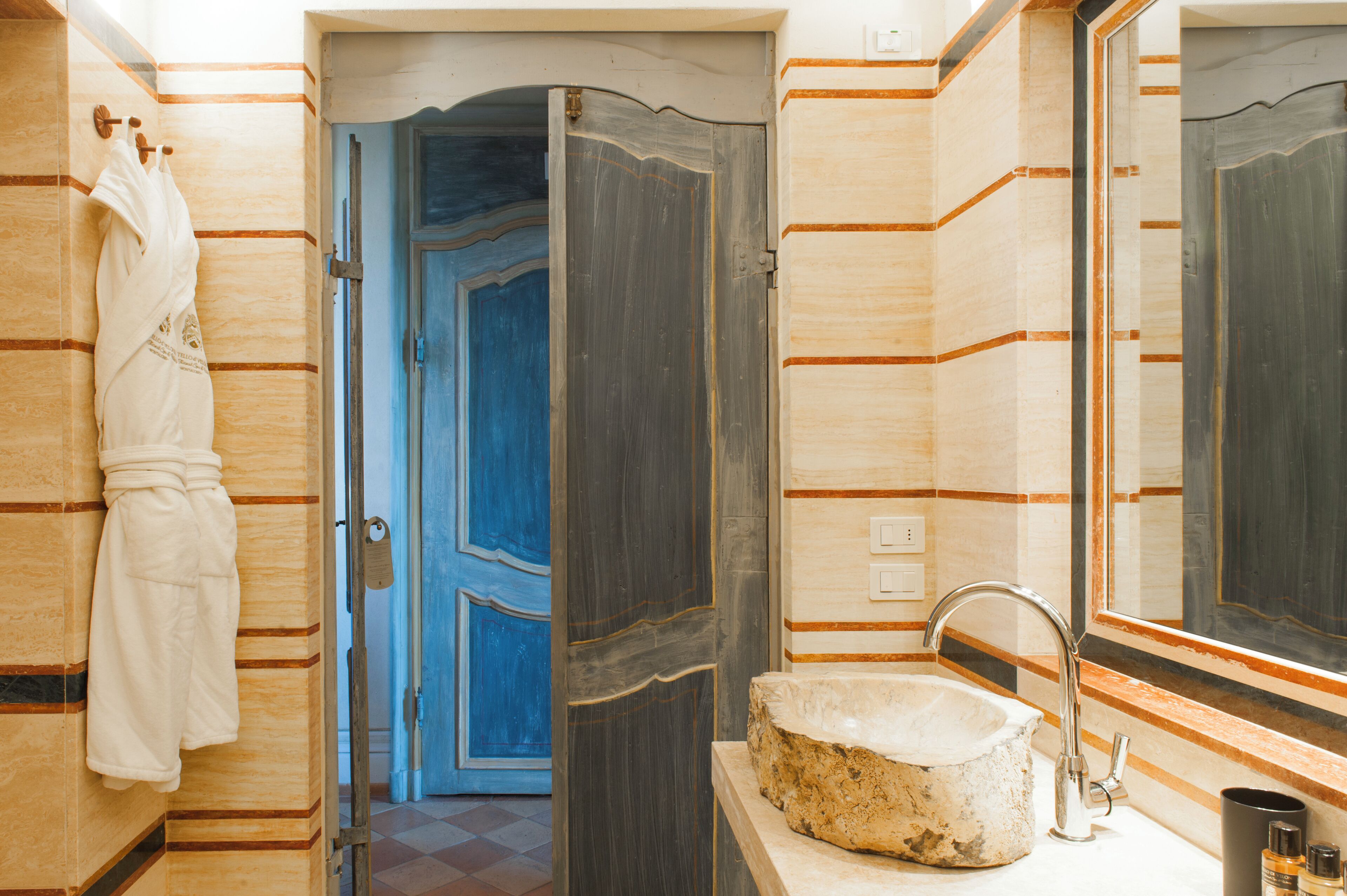 A bathroom with a stone sink, a towel rack, and a mirror.