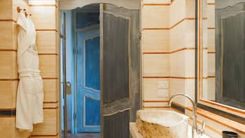 Un baño con un lavabo de piedra, un perchero y un espejo.