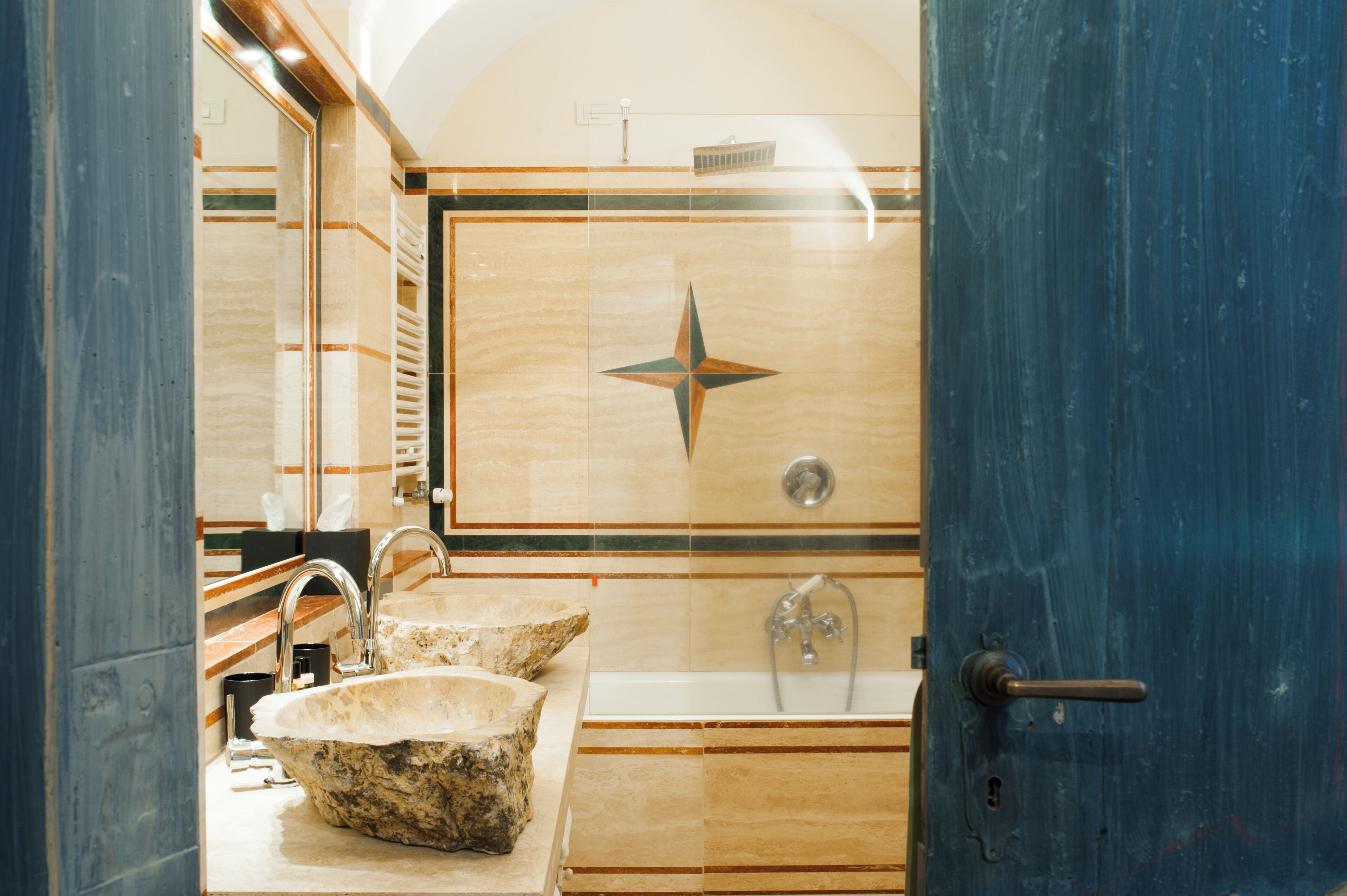 A bathroom with a stone sink, a bathtub, and a mirror.