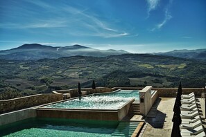 A rooftop infinity pool with a view of rolling hills and mountains. - Castello di Velona Resort Thermal SPA & Winery (Montalcino)